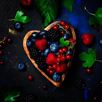 Selection of summer berries in heart shape bowl, food background, top view Stock Photos