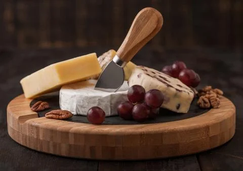 Selection of various cheese on the board and grapes on wood Stock Photos