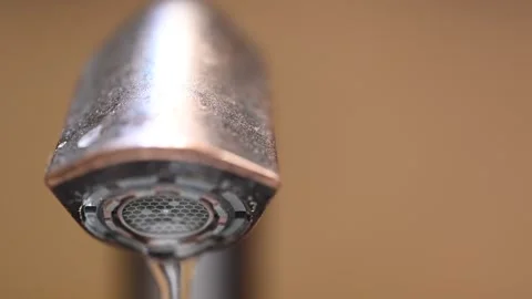 Selective focus on the aerator of a bathroom sink faucet as water is turned on. Stock Footage 229336403