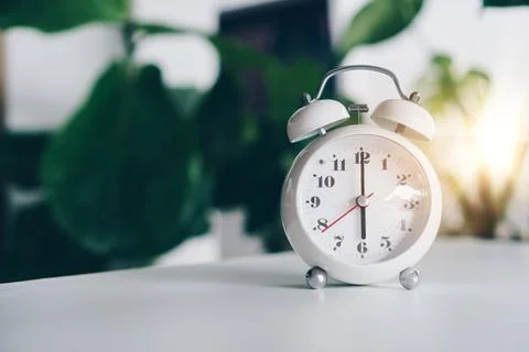 Selective focus of alarm clock show 6 o'clock or 6 a.m. on table with natur.. Stock Photos