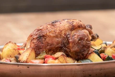 Selective focus and close up of a spit-roasted chicken with baked potatoes an Stock Photos