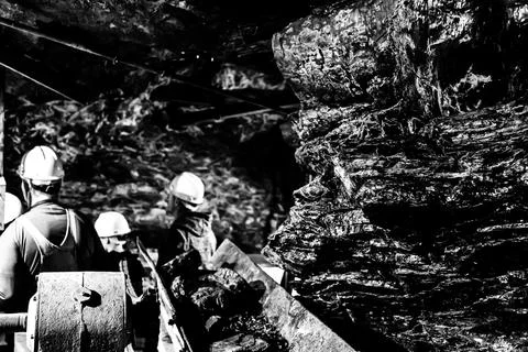 Selective focus on anthracite coal on a conveyer belt with defocused group in Foto stock