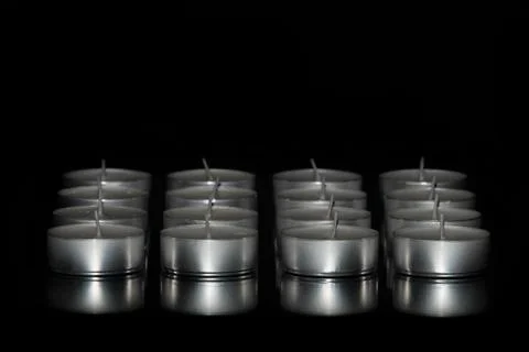 Selective focus of an arrangement of tea light candles on a dark background.  Stock Photos