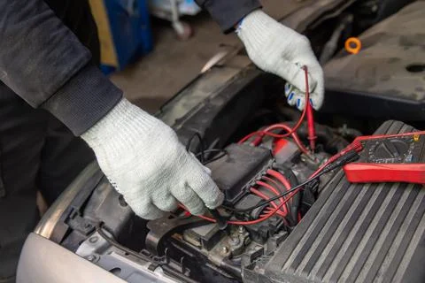 Selective focus an auto mechanic uses a multimeter voltmeter to check the vol Stock Photos