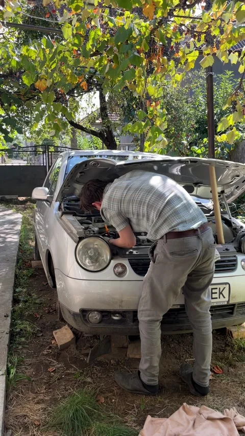 Selective focus automotive technician examining engine in residential yard Stock Footage 346069025