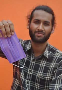 Selective focus of a bearded man showing face mask with his hand for use Stock Photos