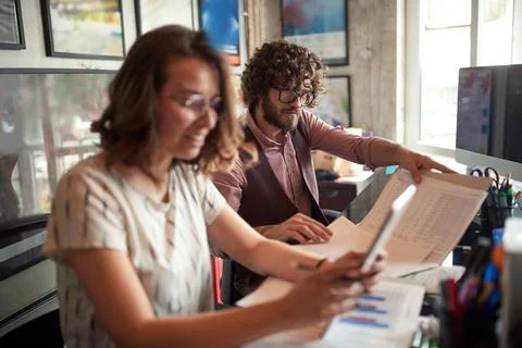 Selective focus on a beardy guy working together with his caucasian young fem Stock Photos