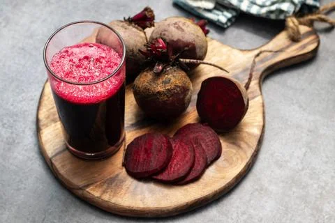 Selective focus of a beet root glass juice with lot of fresh beet roots. Stock Photos