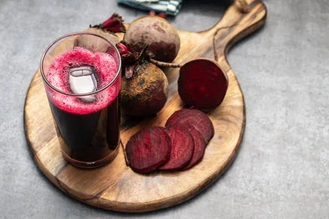Selective focus of a beet root glass juice with lot of fresh beet roots. Stock Photos