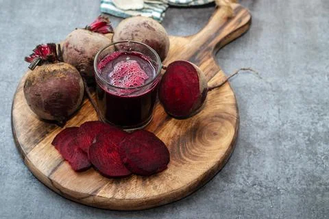 Selective focus of a beet root glass juice with lot of fresh beet roots. Stock Photos