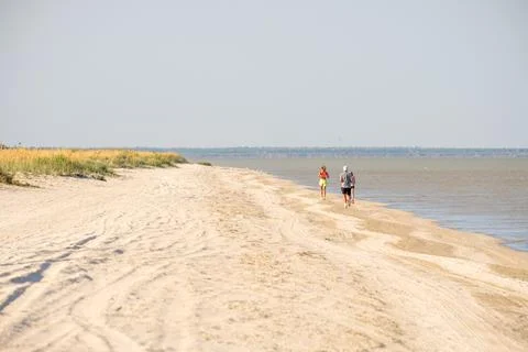 Selective focus from behind on a man running along the beach along the sea. Stock Photos