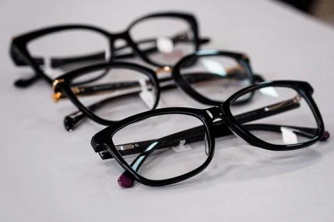 Selective focus black eyeglasses frames arranged on white table surface, op.. Foto stock