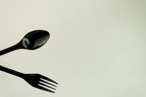Selective focus of black shine spoon and fork with white background. Stock Photos