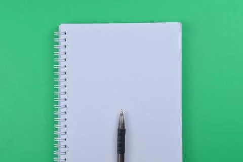 Selective focus of blank notebook and pen on a green background. Business and Stock Photos
