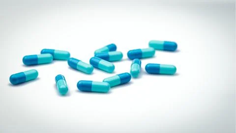 Selective focus on blue capsule pills. Group of capsule pills with shadow spr Foto stock