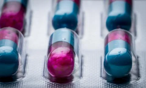 Selective focus of blue, pink capsule with granule in side pills. Pills in bl 库存照片