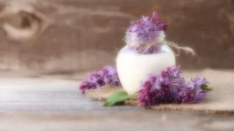 Selective focus, blurred background, lilac flowers in jar with milk on  woode Fotos de archivo