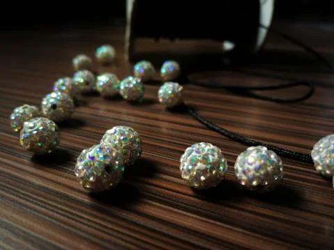 Selective focus with bokeh at one of the white beads with rainbow crystals on Stock Photos