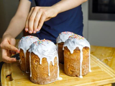 Selective focus of boy hands adding sprinkles on tasty easter cake Stock Photos