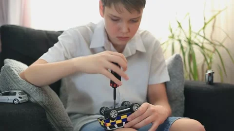 Selective focus. Boy At Home Is Fixing A Toy Car With A Screwdriver. Stock Footage 153319778