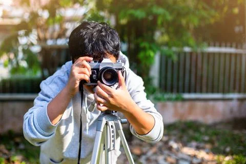 Selective focus to boy taking a picture with film camera and tripod. Stock Photos
