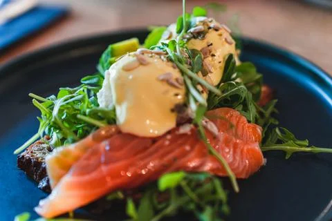 Selective focus on breakfast on the plate. Eggs benedict with salmon, arugula Stock Photos