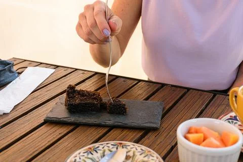 Selective focus on the cake on a slate stone. Brazilian woman eating cookie c Stock Photos