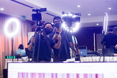 Selective focus to cameramans working with camera and blurry ring lighting .. Stock Photos