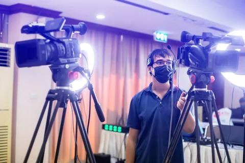 Selective focus to cameramans working with camera and blurry ring lighting .. Stock Photos