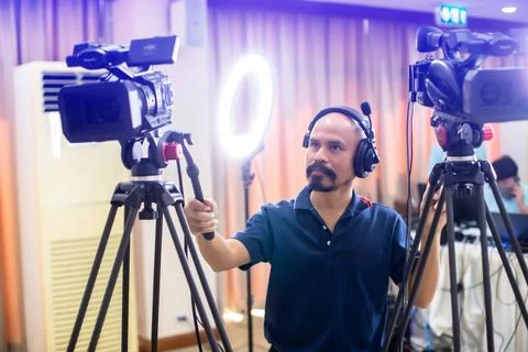 Selective focus to cameramans working with camera and blurry ring lighting .. Stock Photos