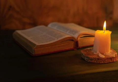 Selective focus of a candle lighting up on a bible. Religious message concept Stock Photos