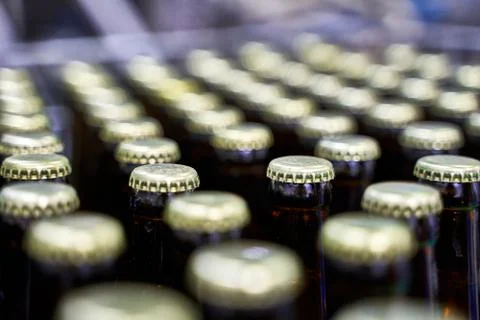 Selective focus on the caps of a group of beer bottles in a brewery Stock Photos