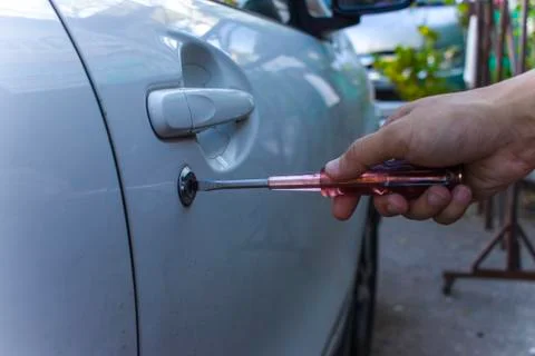 Selective focus on car key remote and tools in man's hand open the car door.  Stock Photos