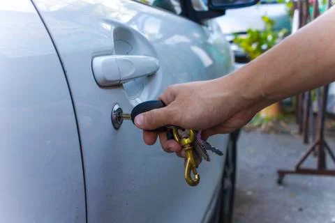 Selective focus on car key remote and tools in man's hand open the car door.  Stock Photos