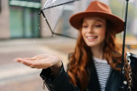 Selective focus of cheerful redhead young woman in stylish hat raising hand up Stock Photos