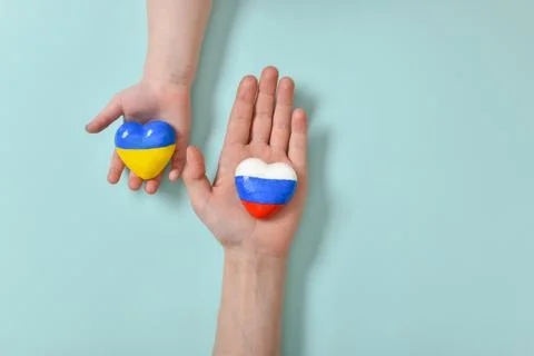 Selective focus. Children's hands hold a heart with the flags of the countrie Stock Photos