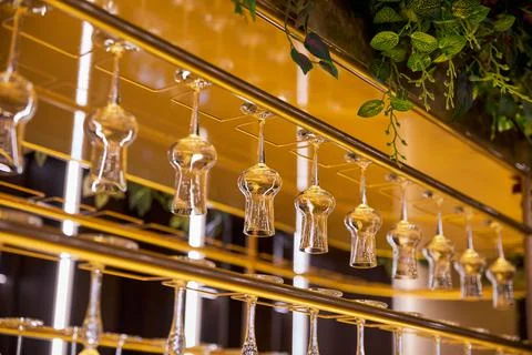 Selective focus of clean empty wine glasses hanging in bar counter Stock Photos