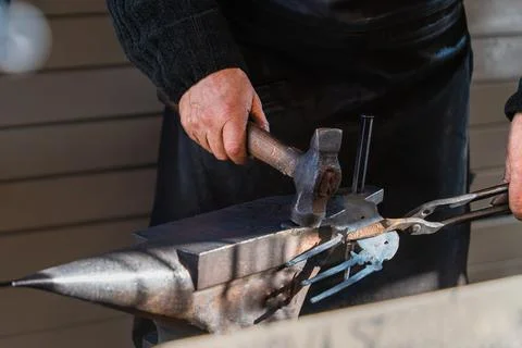 Selective focus close-up of a blacksmith's hand with a hammer metal anvil Stock Photos