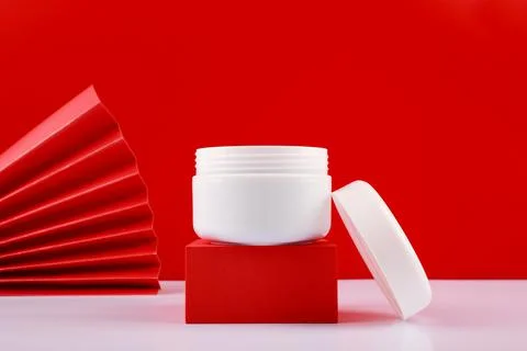 Selective focus, close up of opened jar with cream or mask on red pedestal Stock Photos