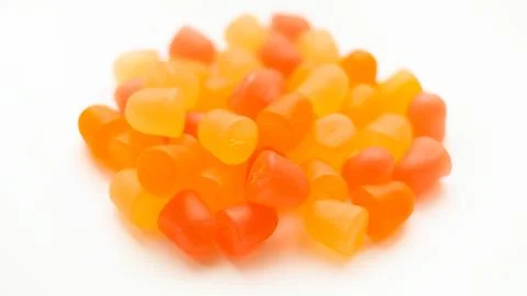 Selective focus, close-up texture of orange and yellow multivitamin gummies on Stock Photos