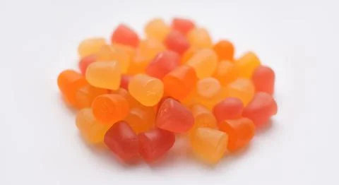 Selective focus, close-up texture of orange and yellow multivitamin gummies on Stock Photos