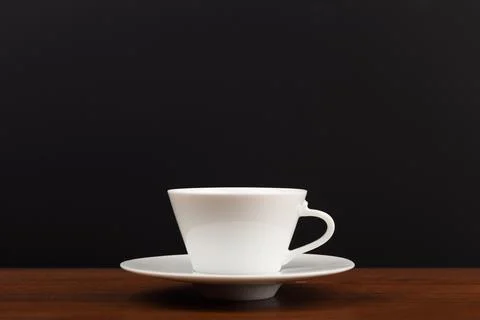 Selective focus, close up of white ceramic coffee or tea cup against dark black Stock Photos