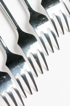Selective focus closeup macro metal shiny forks lined up over white backgroun Stock Photos
