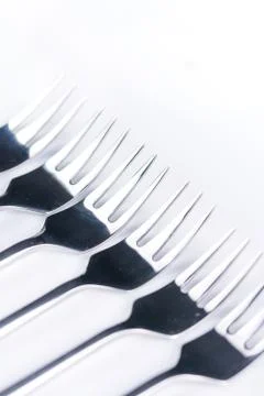 Selective focus closeup macro metal shiny forks lined up over white backgroun Stock Photos