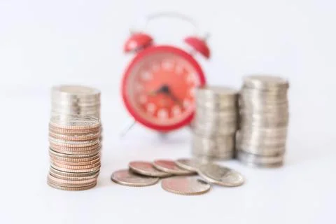 Selective focus on coins front of blur red alarm clock, concept to work at... Foto stock
