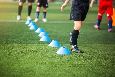 Selective focus to cone marker with blurry kid soccer is running on green art Stock Photos