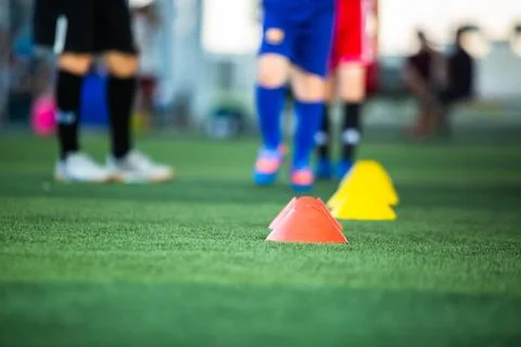 Selective focus to cone marker with blurry soccer team is on green artificial Stockfoto's