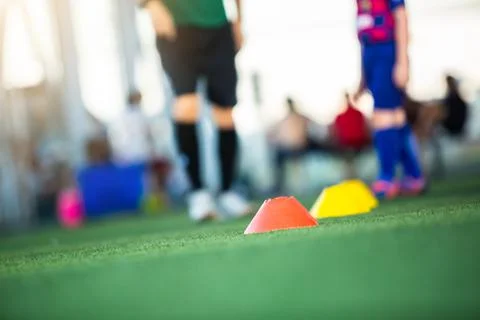 Selective focus to cone marker with blurry soccer team is on green artificial Stock Photos