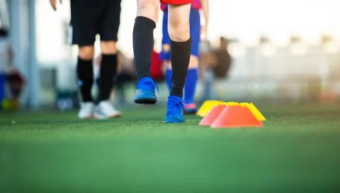 Selective focus to cone marker with blurry soccer team is on green artificial Stockfoto's