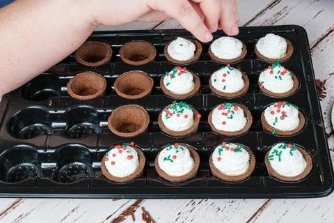 Selective focus. Confectioner decorating the mini pies with colorful spinkles Stock Photos